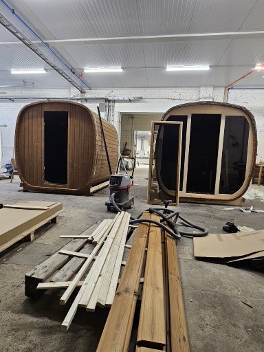 Two Nordic saunas at different stages of production in the workshop
